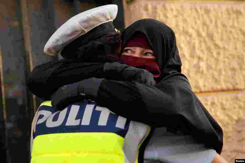 Ayah, 37, wearing a niqab, weeps as she is embraced by a Danish police officer during a demonstration against a ban on the face veil, in Copenhagen, Denmark, Aug. 1, 2018.