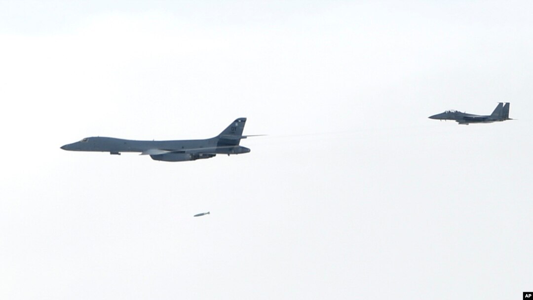 A U.S. Air Force B-1B Lancer bomber, left, drops a bomb over the Korean Peninsula, South Korea, July 8, 2017, in this photo provided by South Korea Defense Ministry. Two U.S. bombers flew to the Korean Peninsula to join fighter jets from South Korea and Japan for a practice bombing run as part of a training mission in response to North Korea's ballistic missile and nuclear programs, officials said Friday.