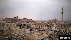 Pripadnik snaga lojalnih sirijskom predsedniku Bašaru al Asadu stoji sa civilom na ruševinama Karlton hotela u delu Alepa koji kontroliše vlada, 17. decembra 2016. (REUTERS/Omar Sanadiki)