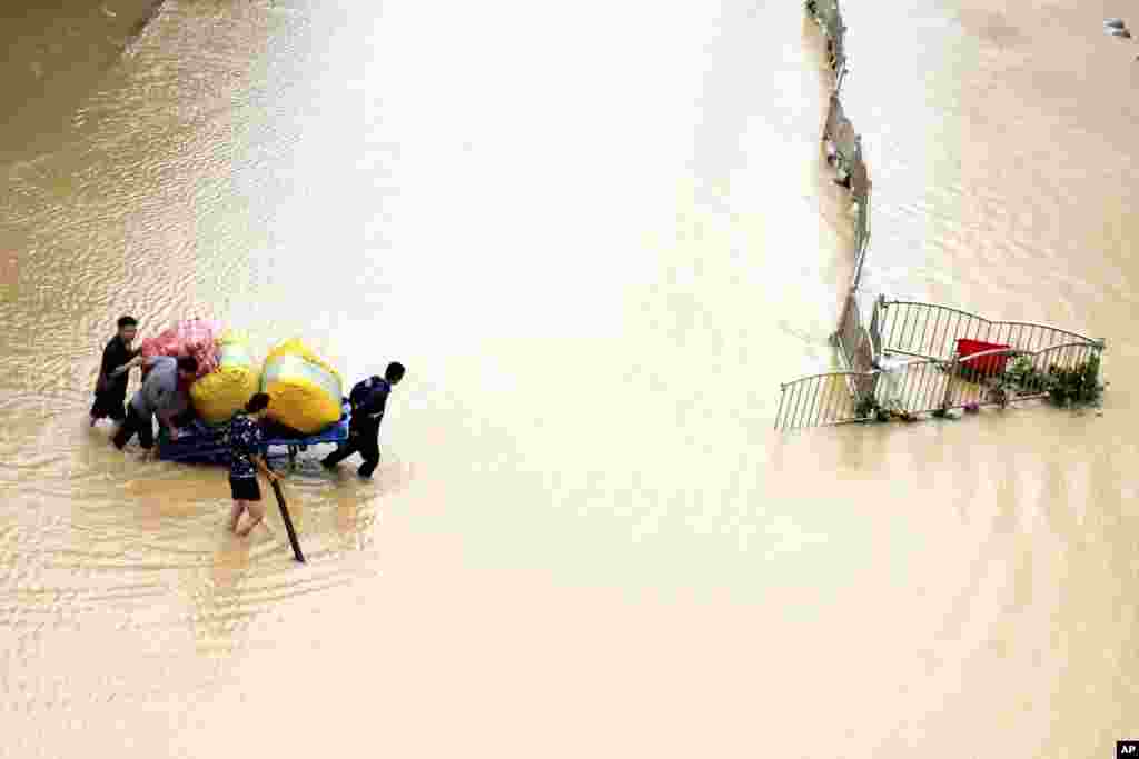 Residents move their belongings across a flooded street in Zhengzhou in central China&#39;s Henan province. (Credit:&nbsp;Xinhua News Agency)