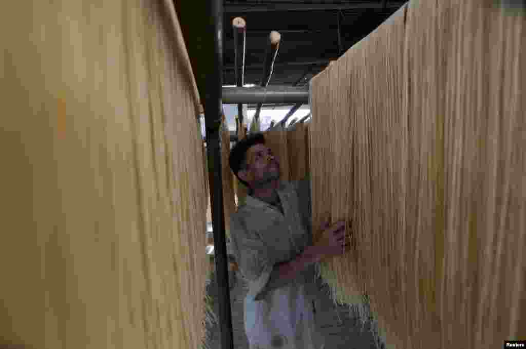 A worker dries noodles, in preparation for the upcoming Eid al-Fitr festival to celebrate the end of the Muslims' holy fasting month of Ramadan, in Rawalpindi, Pakistan.