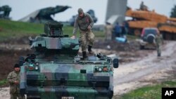 FILE - Turkish soldiers on an armored personnel carrier secure a staging area for troops preparing their tanks to enter combat and join a military offensive on a Kurdish-held enclave in northern Syria, in Hatay province, Turkey, near the the border with 