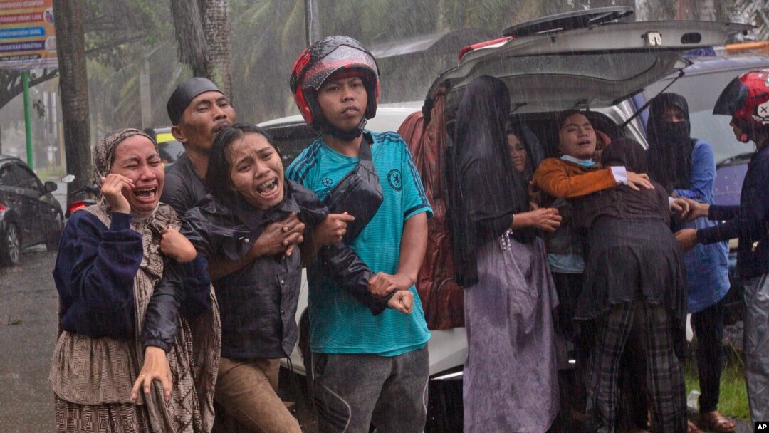People react as the body of a relative is retrieved from the ruin of a building at an area affected by an earthquake in Mamuju, West Sulawesi, Indonesia, Jan. 15, 2021.