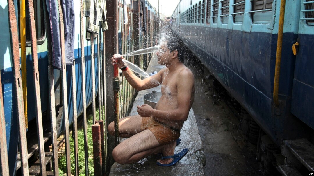 An Indian passenger takes a bath beside rail tracks on a hot summer day at a railway station in Jammu, India, Monday, May 25, 2015. Severe heat wave conditions continue to prevail at several places in northern India with temperatures reaching 48 degrees C