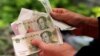 A customer counts Chinese Yuan banknotes as she purchases vegetables at a market in Beijing, China, May 9, 2016. 