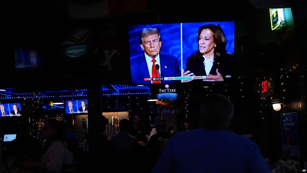 People watch TV screens showing the debate between Democratic presidential nominee Vice President Kamala Harris, right, and Republican presidential nominee former President Donald Trump at Sports Grill Kendall in Miami, Florida, Sept. 10, 2024. 