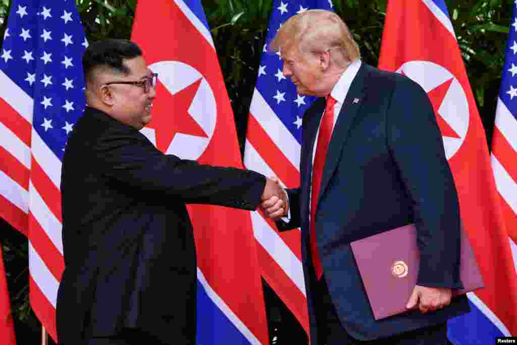 U.S. President Donald Trump and North Korea's leader Kim Jong Un shake hands during the signing of a document after their summit at the Capella Hotel on Sentosa island in Singapore.