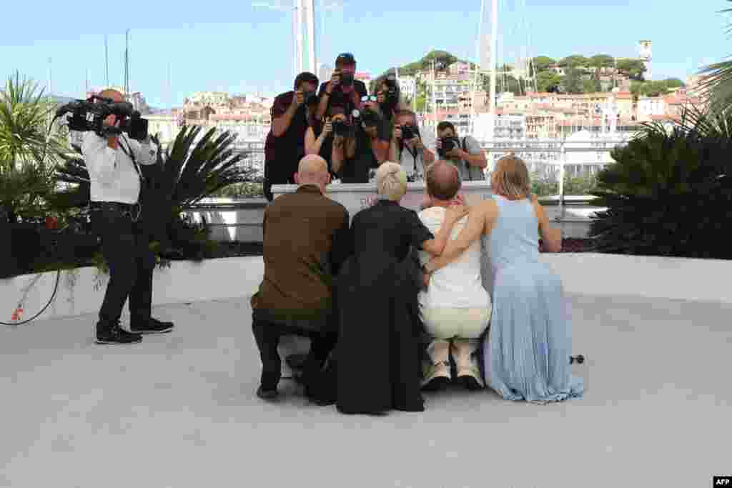 (From L) Russian actors Yuri Kolokolnikov, Chulpan Khamatova, Ivan Dorn and Yuliya Peresild hide behind the podium during a photocall for the film "Petrov's Flu" at the 74th edition of the Cannes Film Festival in Cannes, France.