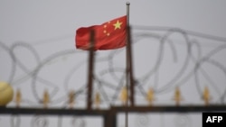 資料照片：在新疆喀什市以南的一個居住區，一面中國國旗在鐵絲網後面飄揚。 (2019年6月4日)